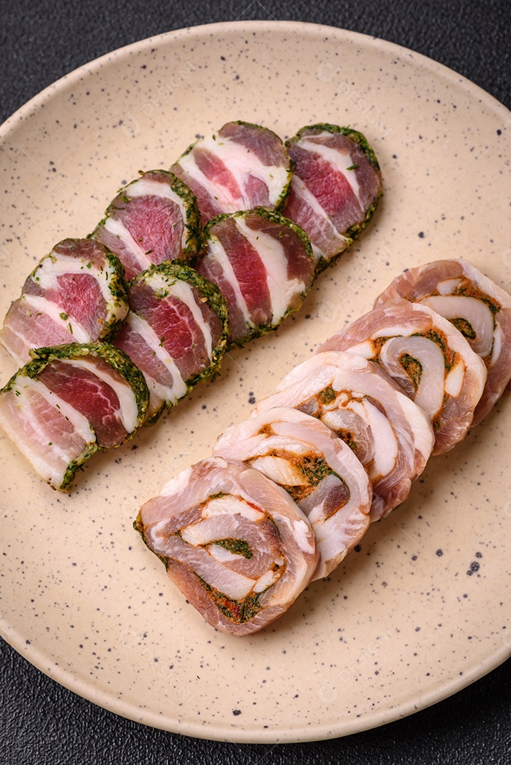 Bolo de carne delicioso com banha, sal, especiarias e ervas cortadas em fatias sobre um fundo escuro de concreto