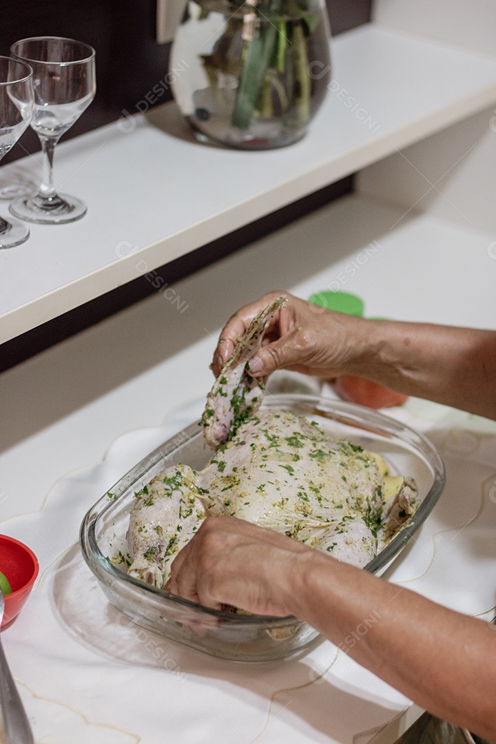 Mão de pessoa temperando frango para assa para céia de natal