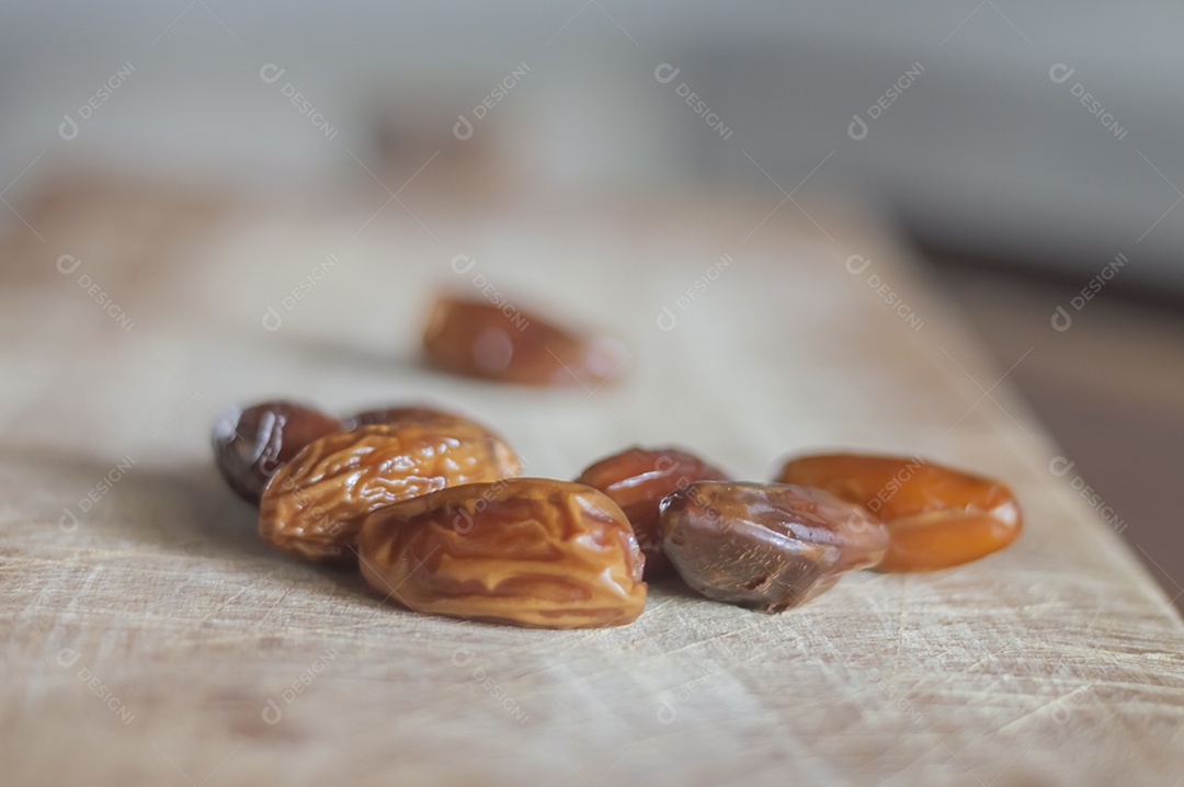 Tâmara desidratada sobre tábua de madeira, foto com luz natural.