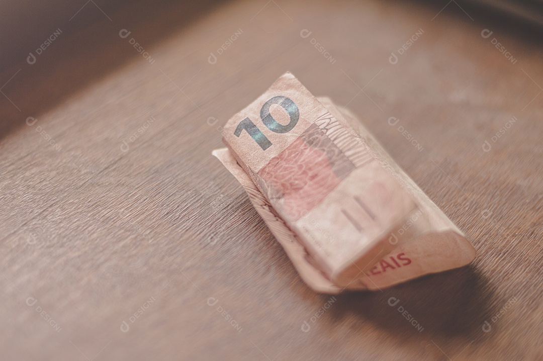 Nota de dez reais, 10 reais em mesa de madeira com luz natural, dinheiro brasileiro, nota de dez reais.