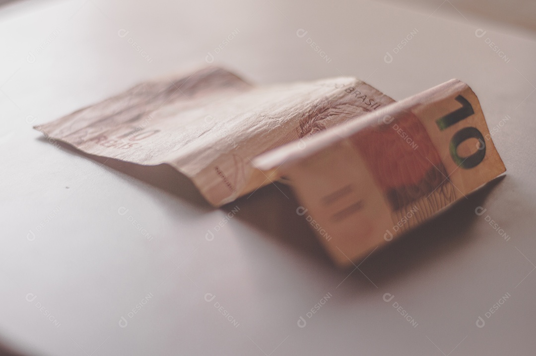 Nota de dez reais, 10 reais em mesa de madeira com luz natural, dinheiro brasileiro, nota de dez reais.