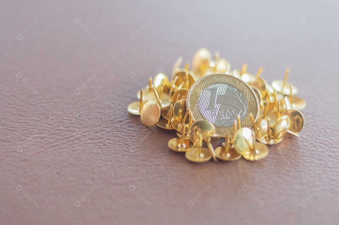 1 moeda real, dinheiro brasileiro com peças de ouro ao fundo