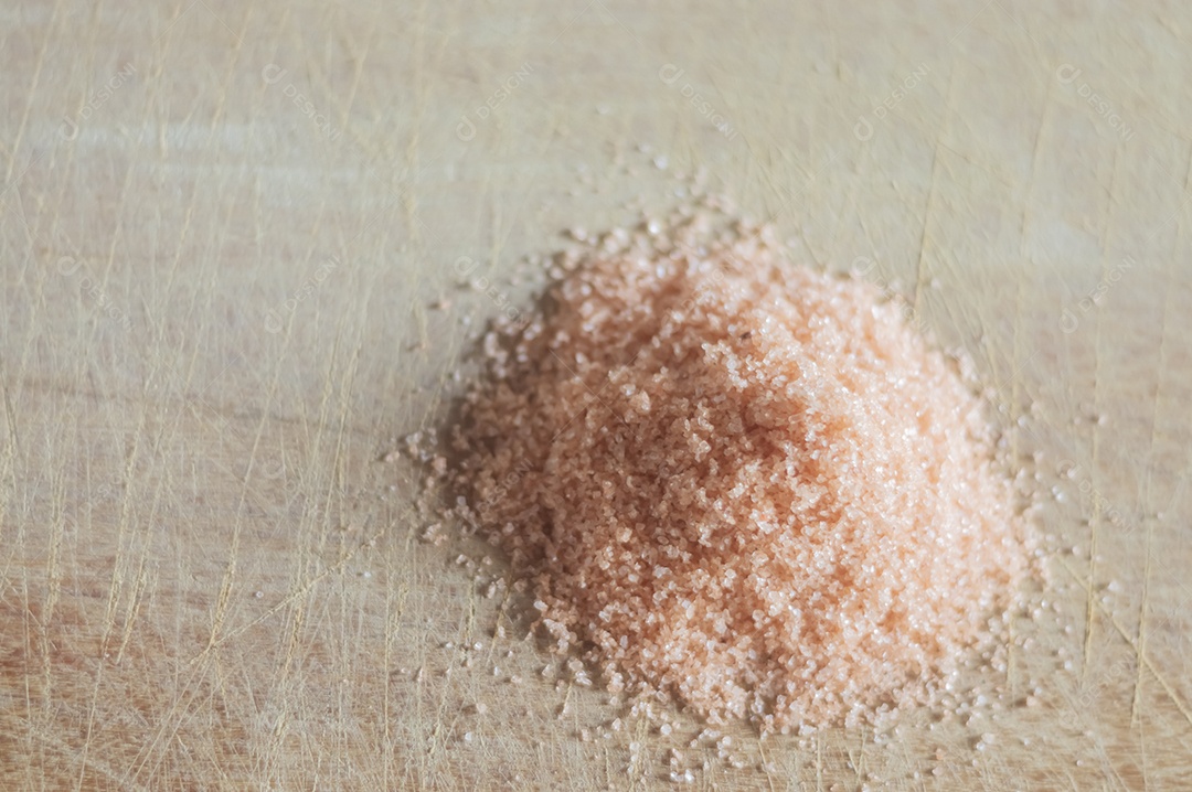 Sal do Himalaia em uma tábua de madeira com luz natural, sal vermelho.