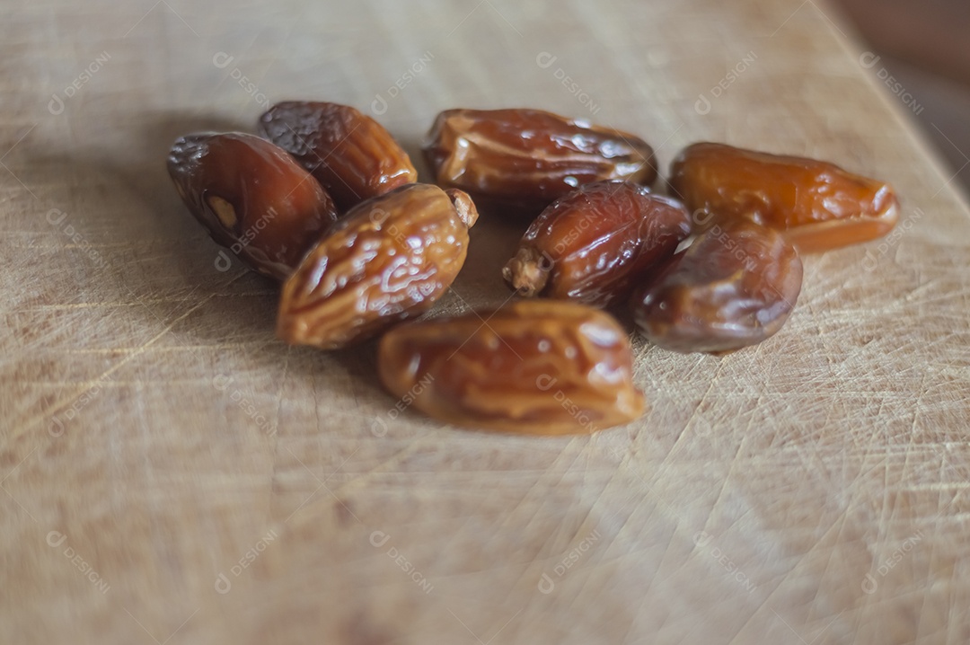Tâmara desidratada sobre tábua de madeira, foto com luz natural.
