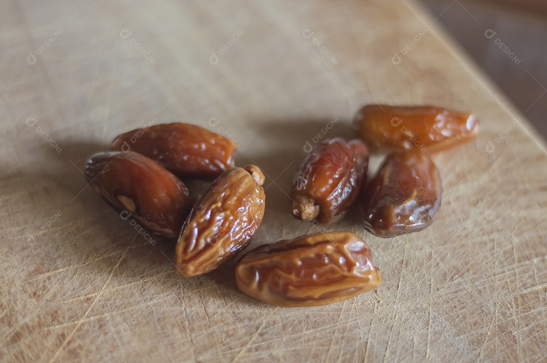 Tâmara desidratada sobre tábua de madeira, foto com luz natural.