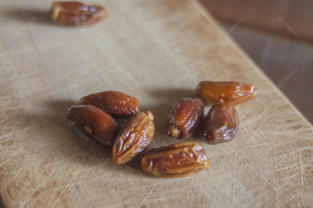 Tâmara desidratada sobre tábua de madeira, foto com luz natural.