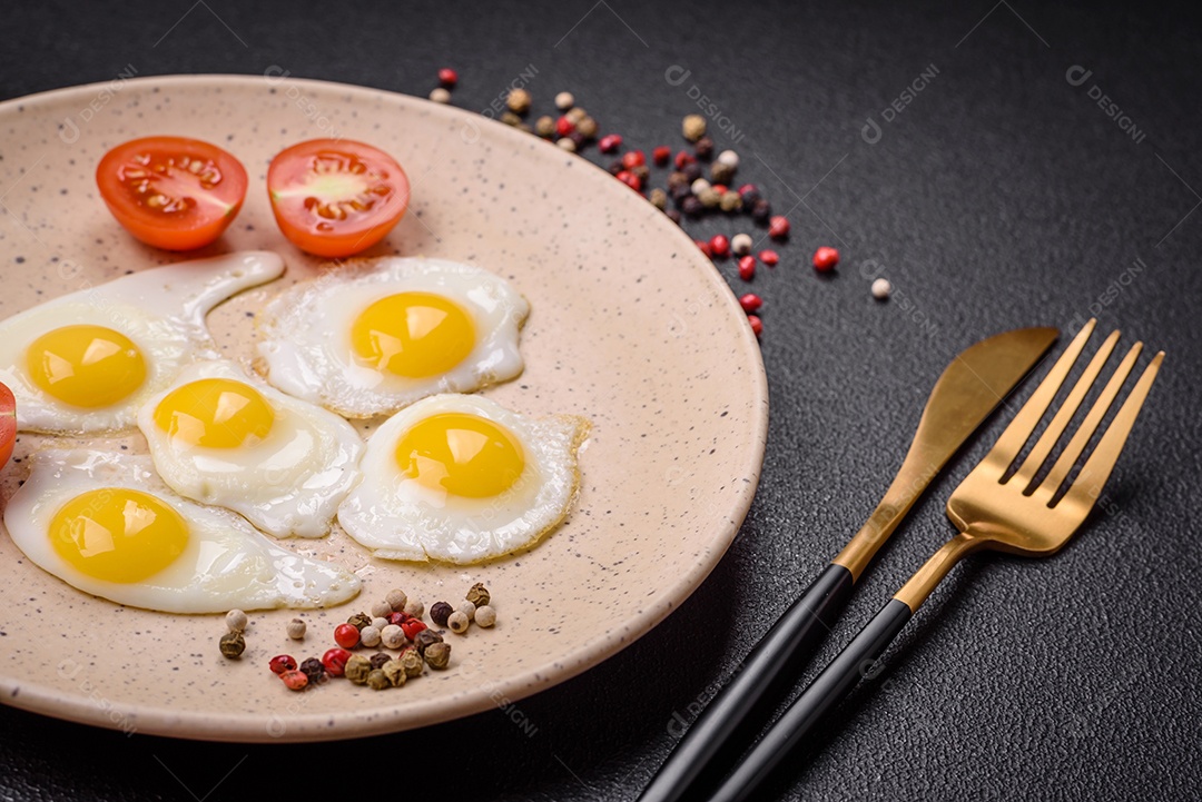 Delicioso café da manhã nutritivo com ovos de codorna fritos, bacon, legumes e tomate cereja com sal, especiarias