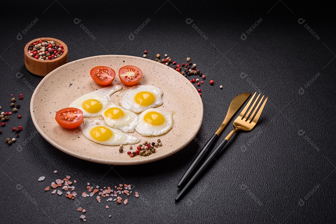 Delicioso café da manhã nutritivo com ovos de codorna fritos, bacon, legumes e tomate cereja com sal, especiarias