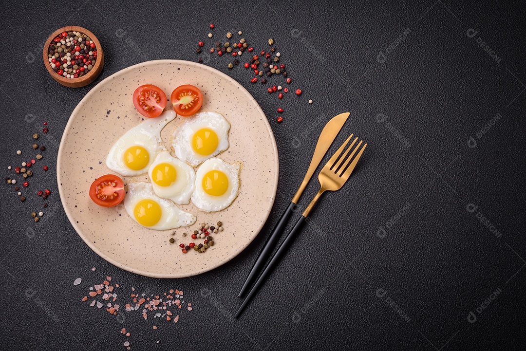 Delicioso café da manhã nutritivo com ovos de codorna fritos, bacon, legumes e tomate cereja com sal, especiarias