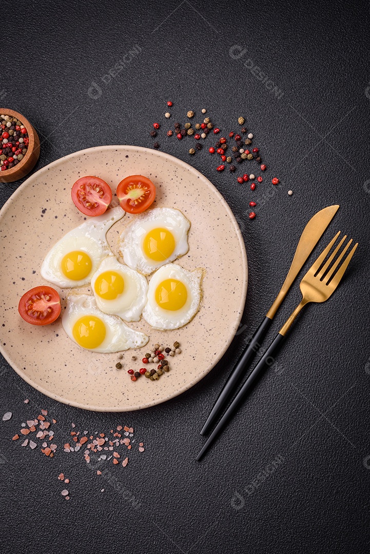 Delicioso café da manhã nutritivo com ovos de codorna fritos, bacon, legumes e tomate cereja com sal, especiarias
