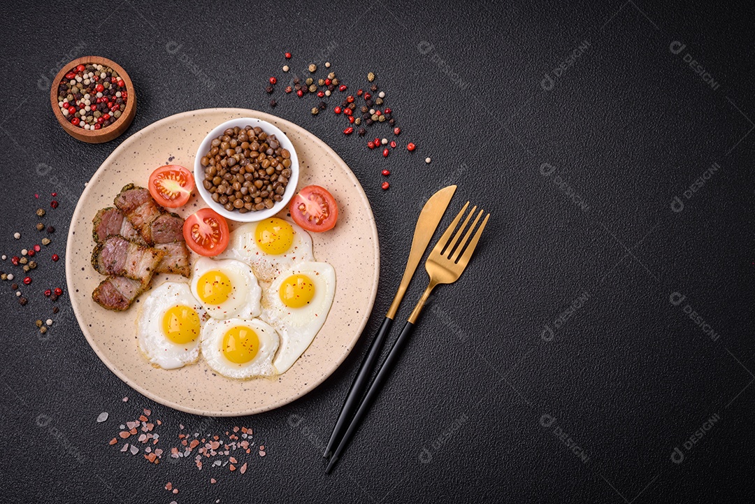 Delicioso café da manhã nutritivo com ovos de codorna fritos, bacon, legumes e tomate cereja com sal, especiarias