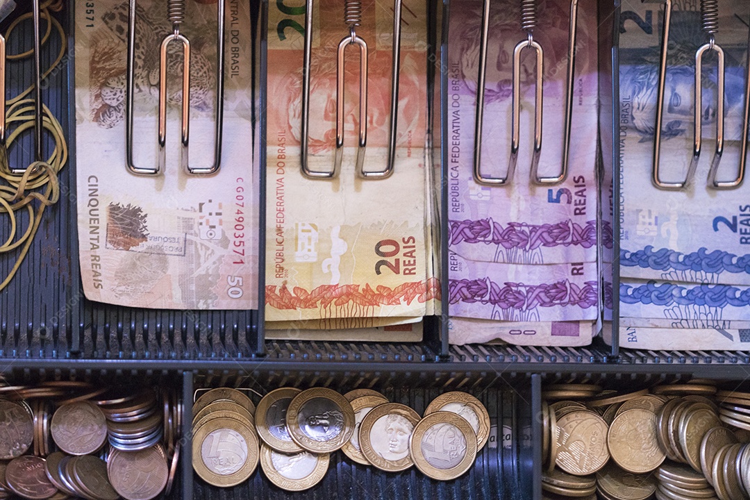 Notas e moedas brasileiras dentro da caixa registradora eletrônica