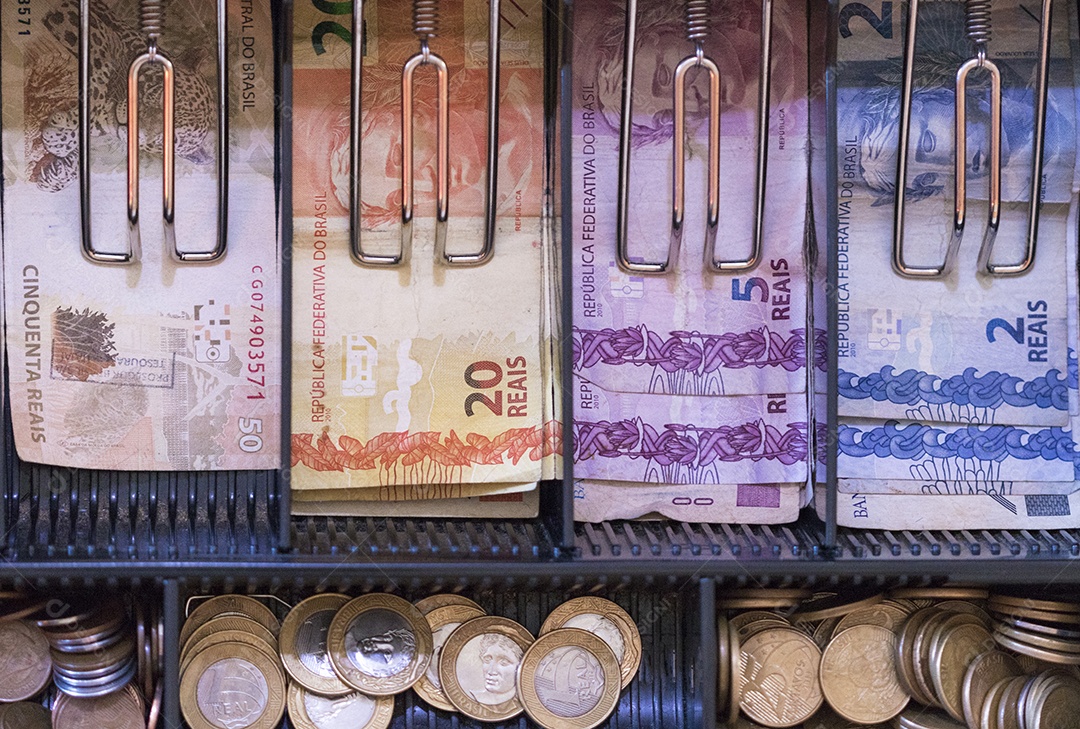 Notas e moedas brasileiras dentro da caixa registradora eletrônica