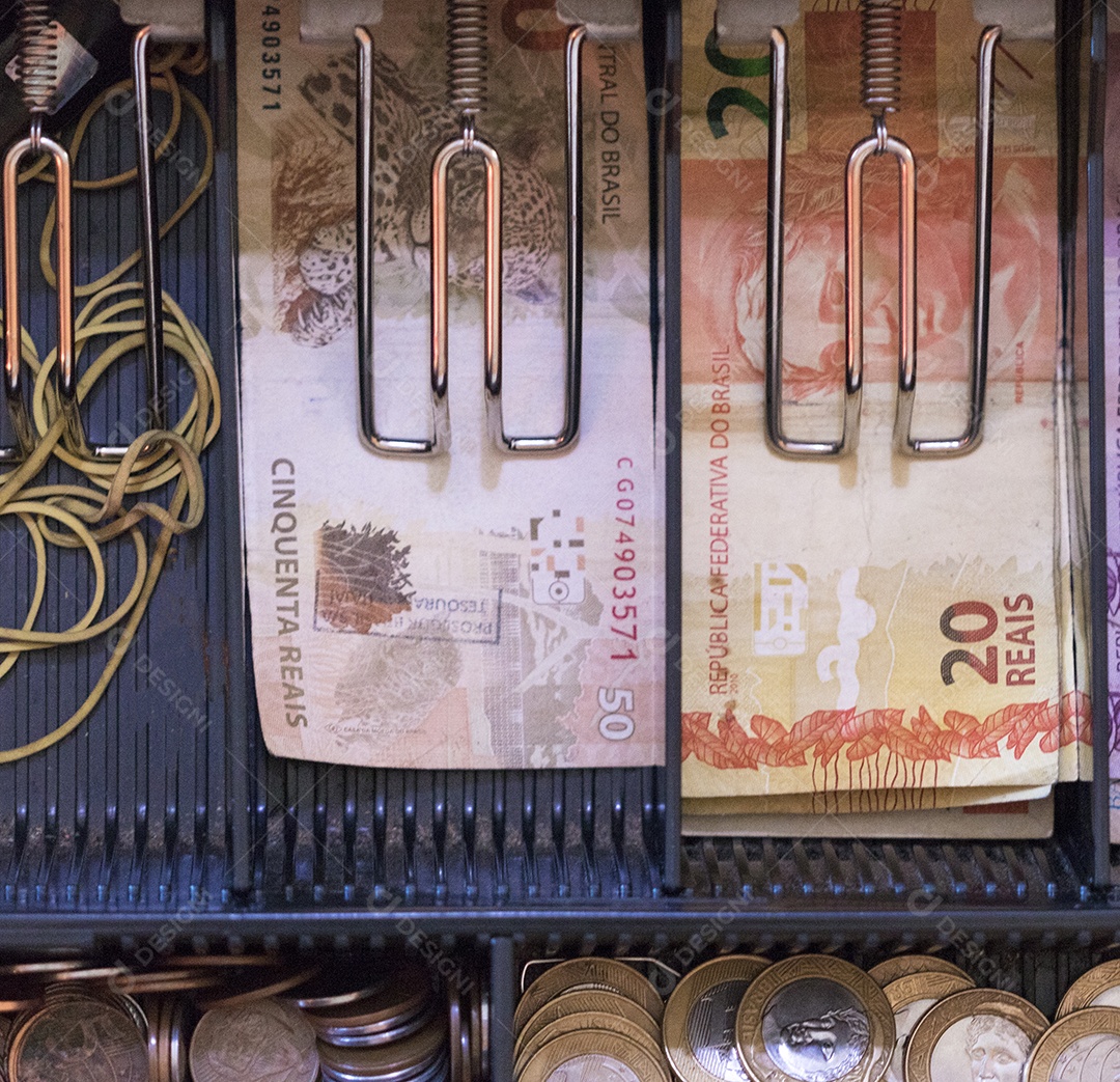 Notas e moedas brasileiras dentro da caixa registradora eletrônica