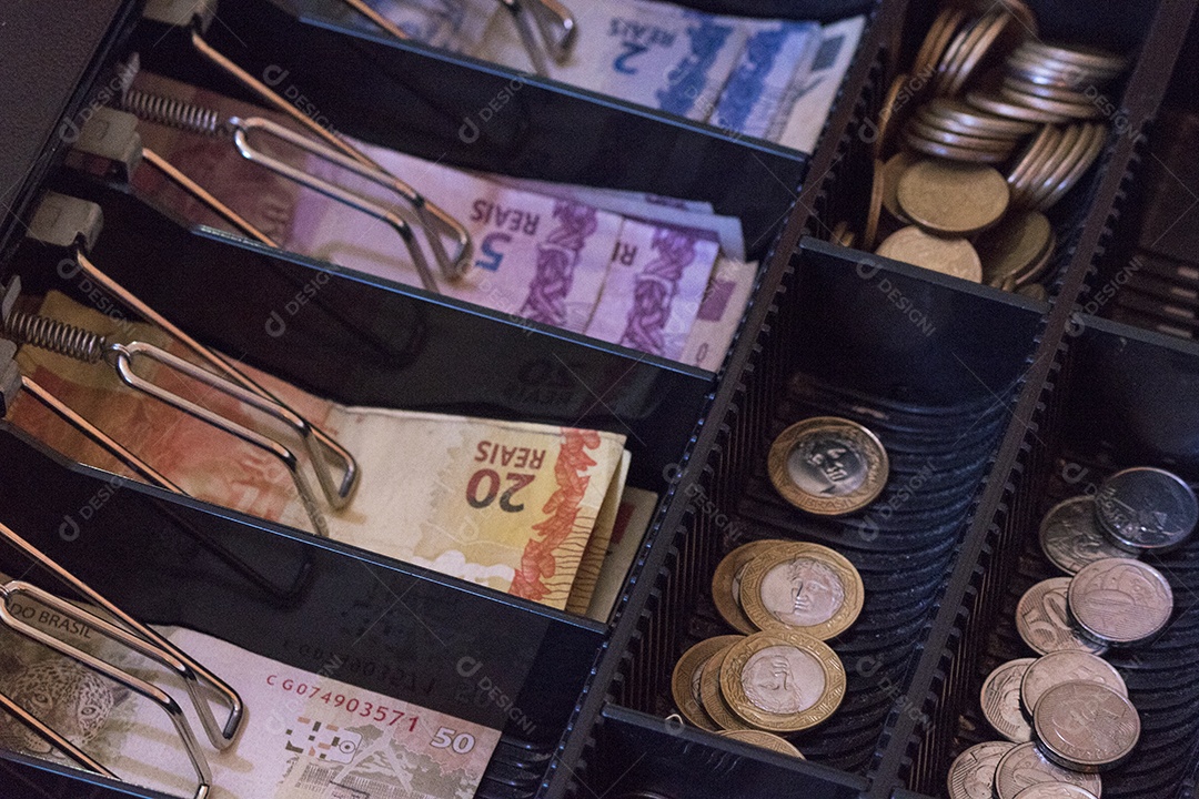 Notas e moedas brasileiras dentro da caixa registradora eletrônica