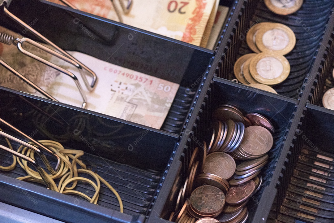 Notas e moedas brasileiras dentro da caixa registradora eletrônica
