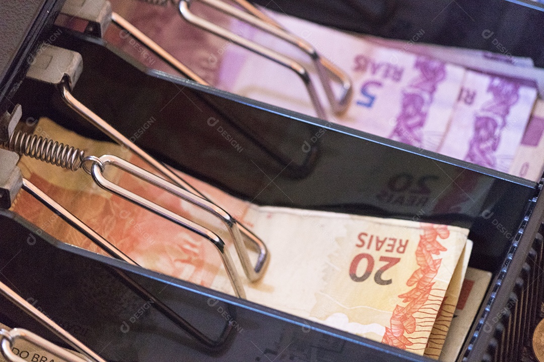 Notas e moedas brasileiras dentro da caixa registradora eletrônica