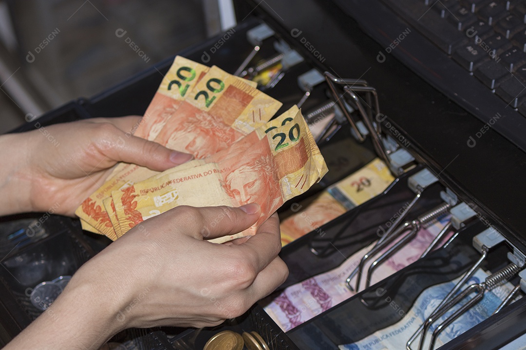 Notas e moedas brasileiras dentro do caixa eletrônico