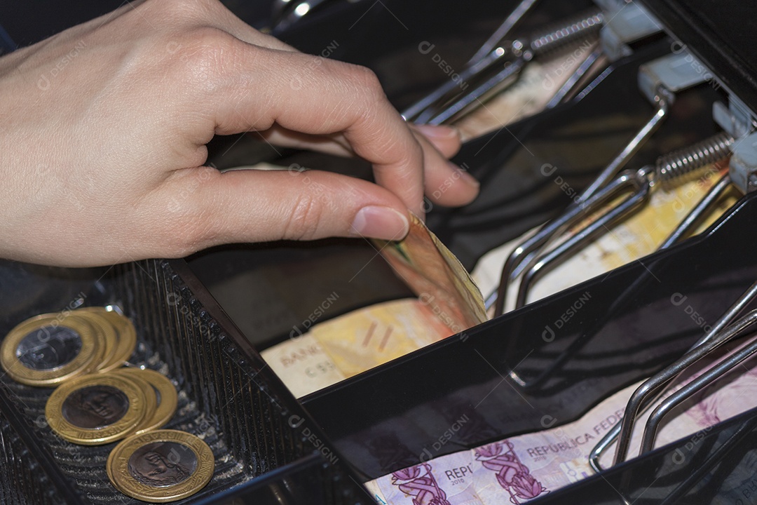 Notas e moedas brasileiras dentro do caixa eletrônico