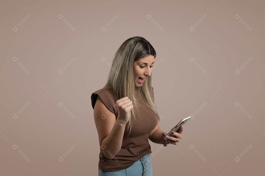 Jovem com cabelo comprido em pé dentro de casa usando telefone celular