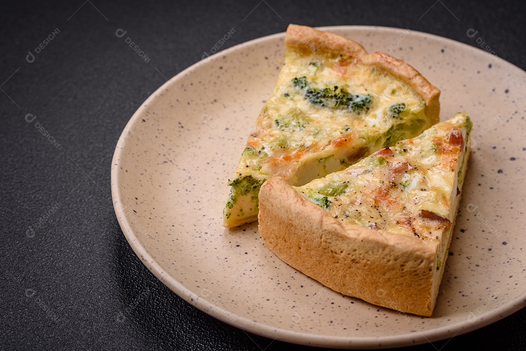 Deliciosa quiche com brócolis, queijo, frango, especiarias e ervas sobre um fundo escuro de concreto