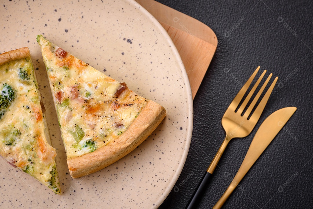 Deliciosa quiche com brócolis, queijo, frango, especiarias e ervas sobre um fundo escuro de concreto