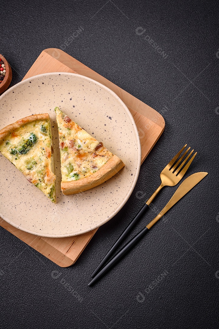 Deliciosa quiche com brócolis, queijo, frango, especiarias e ervas sobre um fundo escuro de concreto