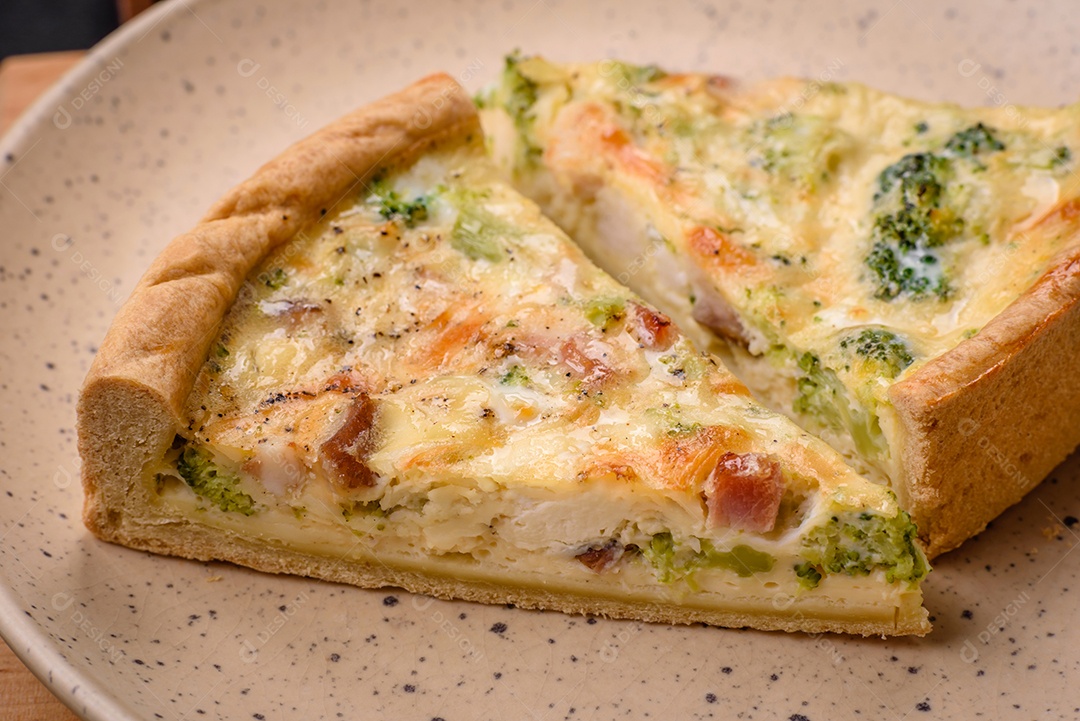 Deliciosa quiche com brócolis, queijo, frango, especiarias e ervas sobre um fundo escuro de concreto