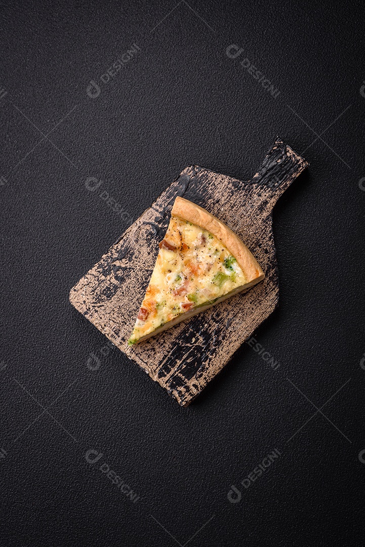 Deliciosa quiche com brócolis, queijo, frango, especiarias e ervas sobre um fundo escuro de concreto