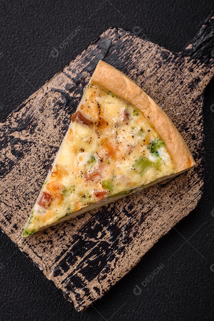 Deliciosa quiche com brócolis, queijo, frango, especiarias e ervas sobre um fundo escuro de concreto