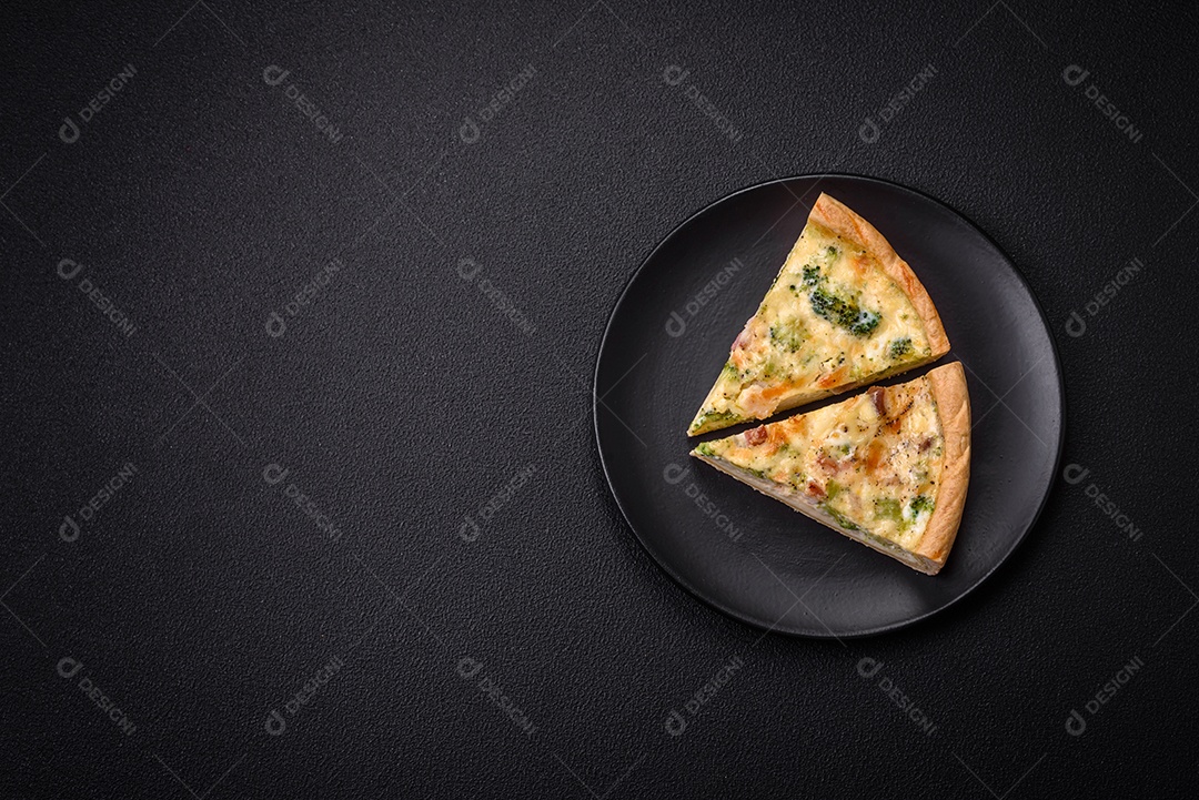 Deliciosa quiche com brócolis, queijo, frango, especiarias e ervas sobre um fundo escuro de concreto
