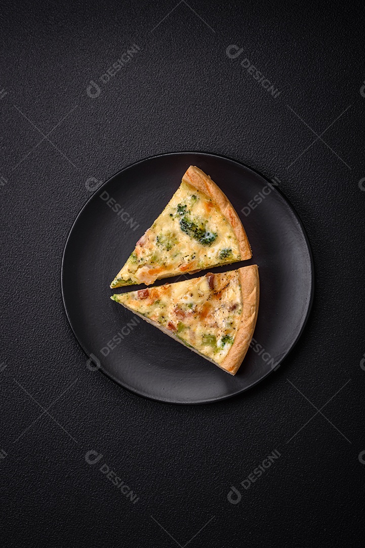 Deliciosa quiche com brócolis, queijo, frango, especiarias e ervas sobre um fundo escuro de concreto
