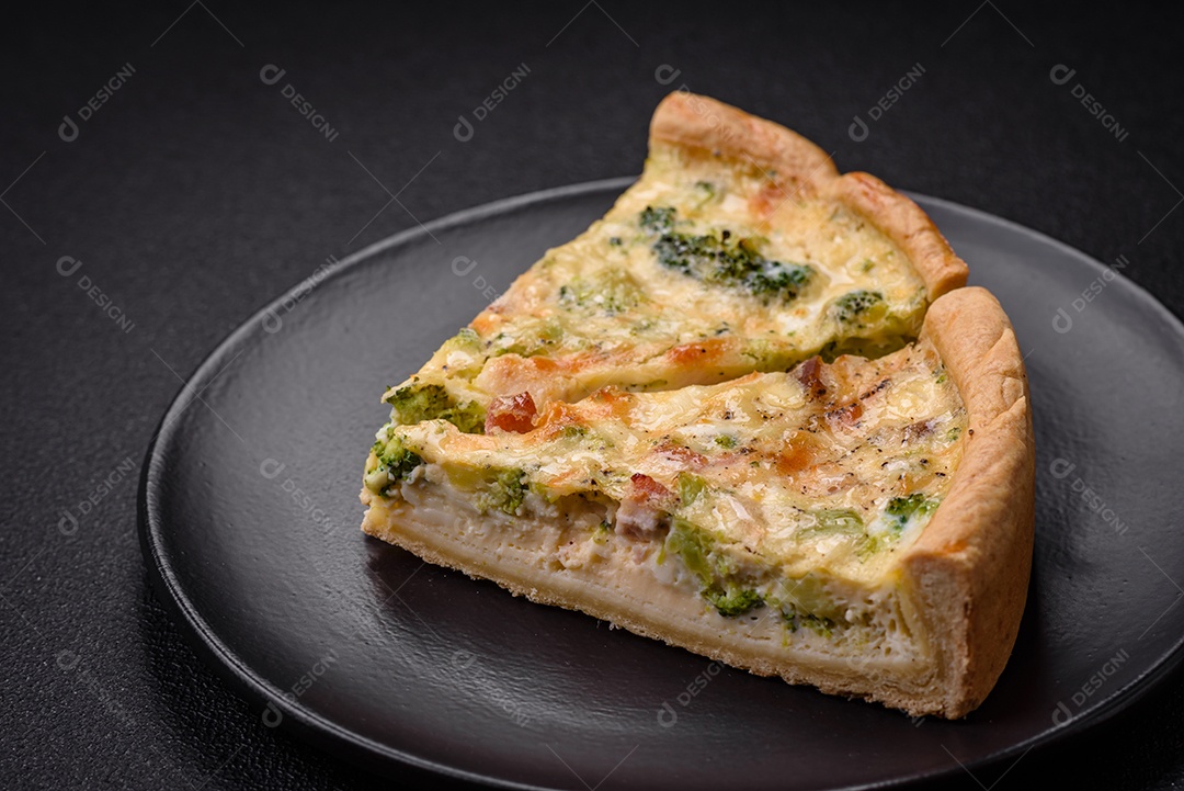 Deliciosa quiche com brócolis, queijo, frango, especiarias e ervas sobre um fundo escuro de concreto