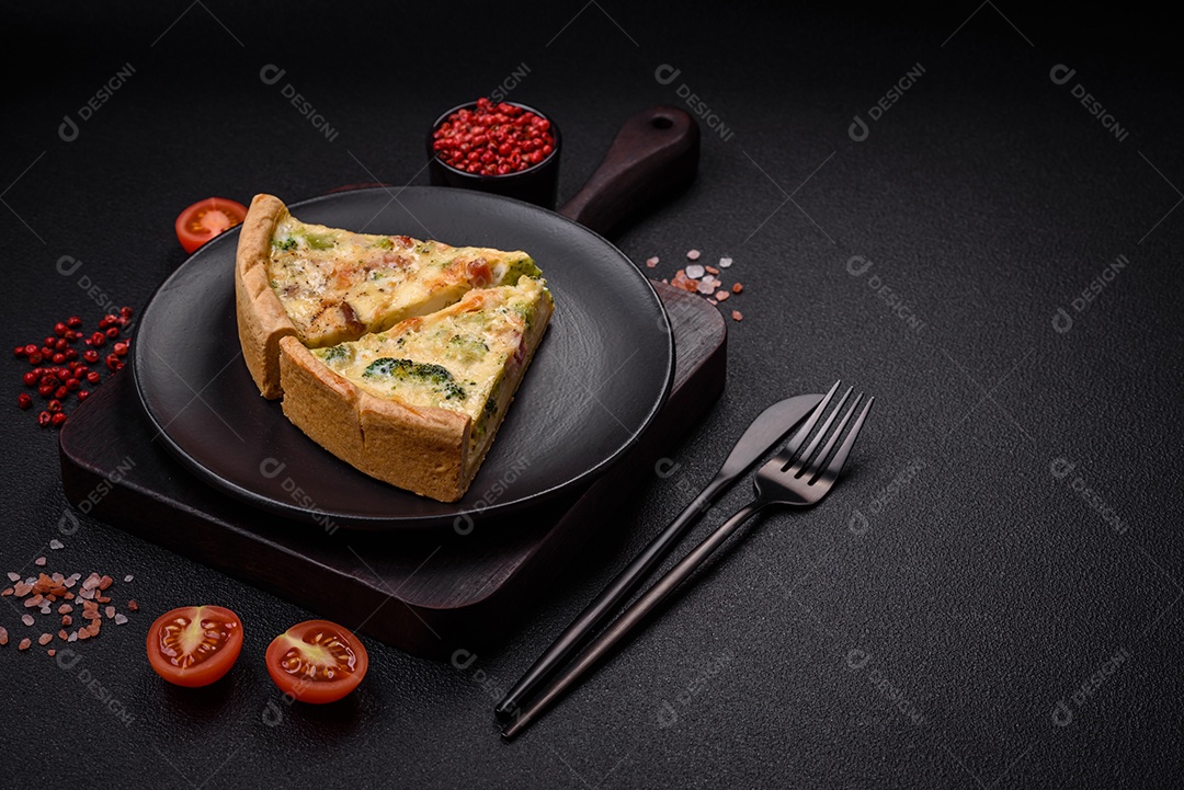 Deliciosa quiche com brócolis, queijo, frango, especiarias e ervas sobre um fundo escuro de concreto