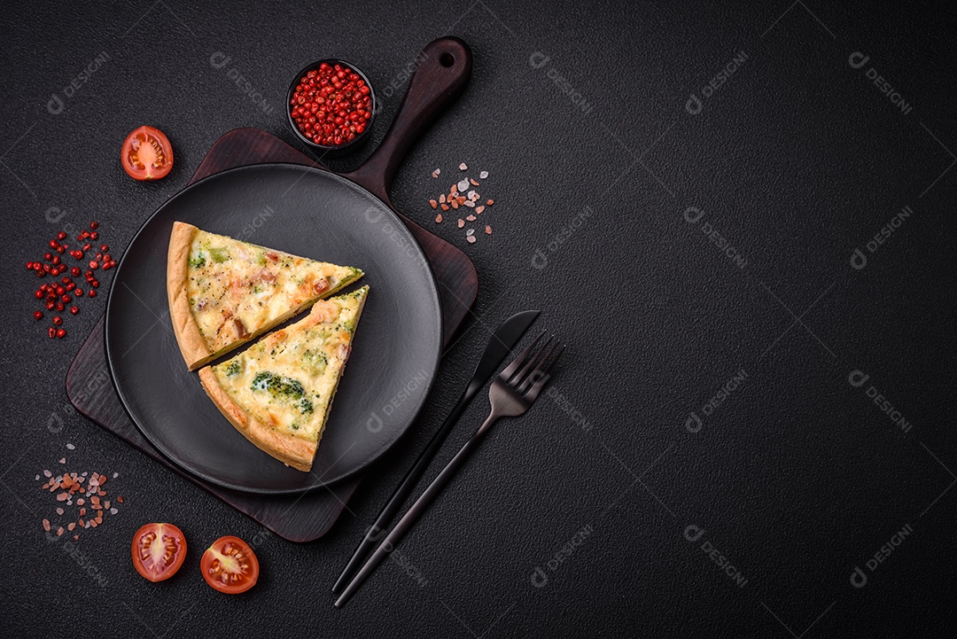 Deliciosa quiche com brócolis, queijo, frango, especiarias e ervas sobre um fundo escuro de concreto