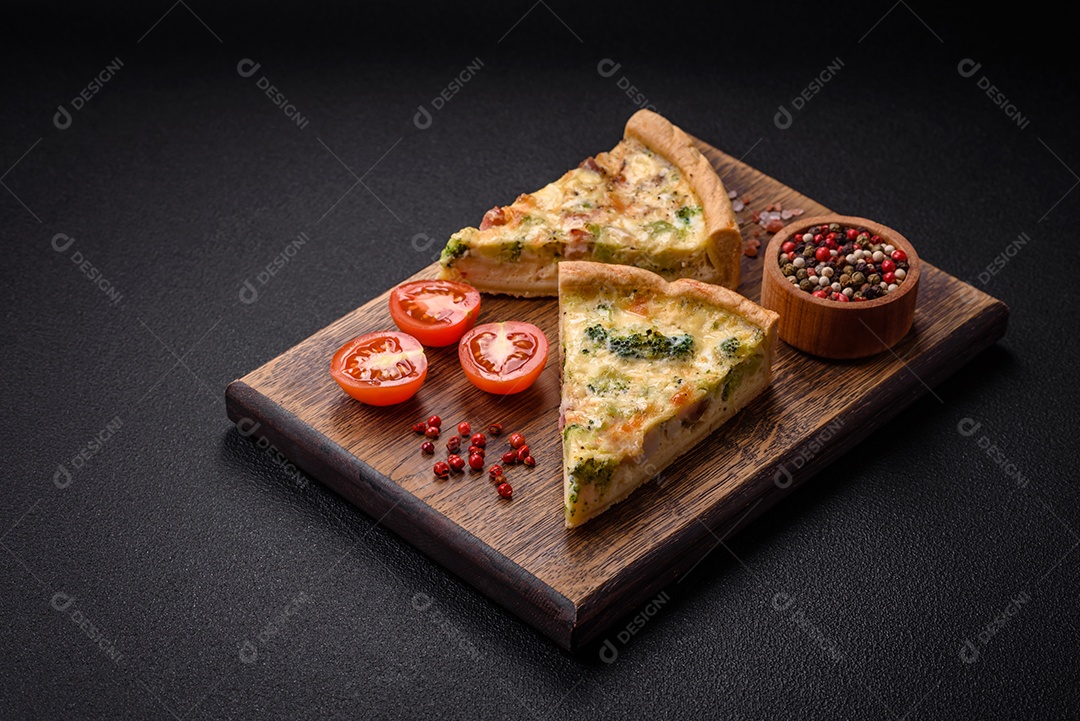 Deliciosa quiche com brócolis, queijo, frango, especiarias e ervas sobre um fundo escuro de concreto