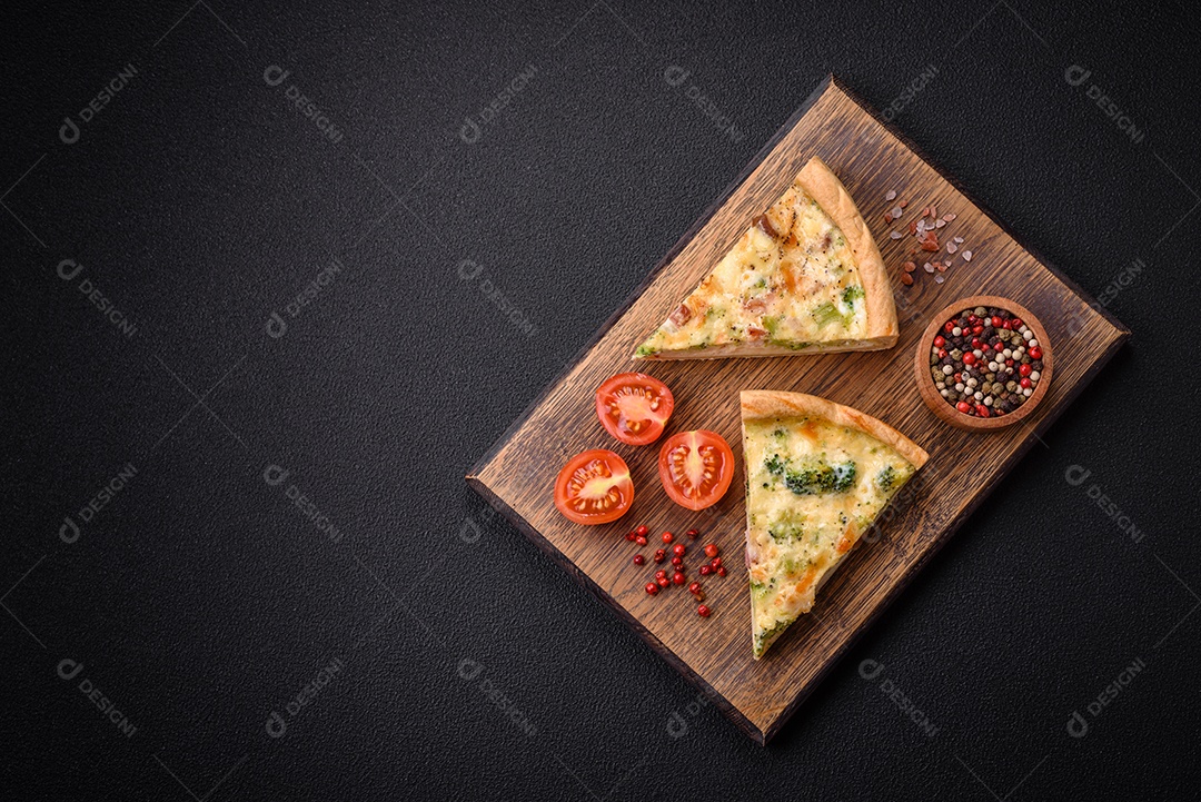 Deliciosa quiche com brócolis, queijo, frango, especiarias e ervas sobre um fundo escuro de concreto