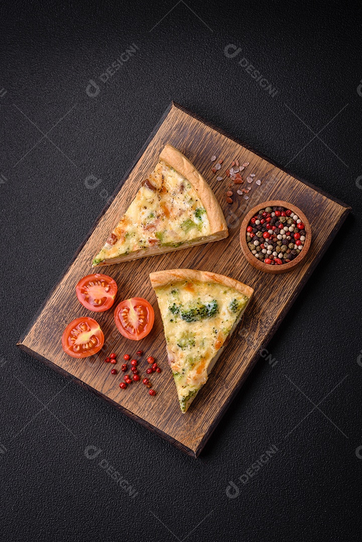 Deliciosa quiche com brócolis, queijo, frango, especiarias e ervas sobre um fundo escuro de concreto