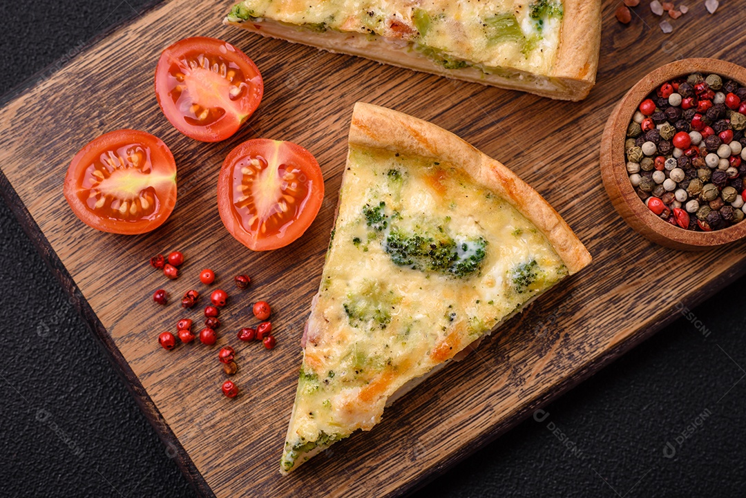 Deliciosa quiche com brócolis, queijo, frango, especiarias e ervas sobre um fundo escuro de concreto