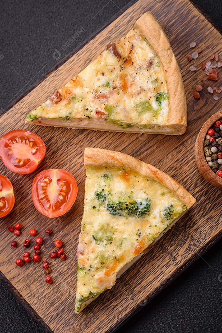 Deliciosa quiche com brócolis, queijo, frango, especiarias e ervas sobre um fundo escuro de concreto