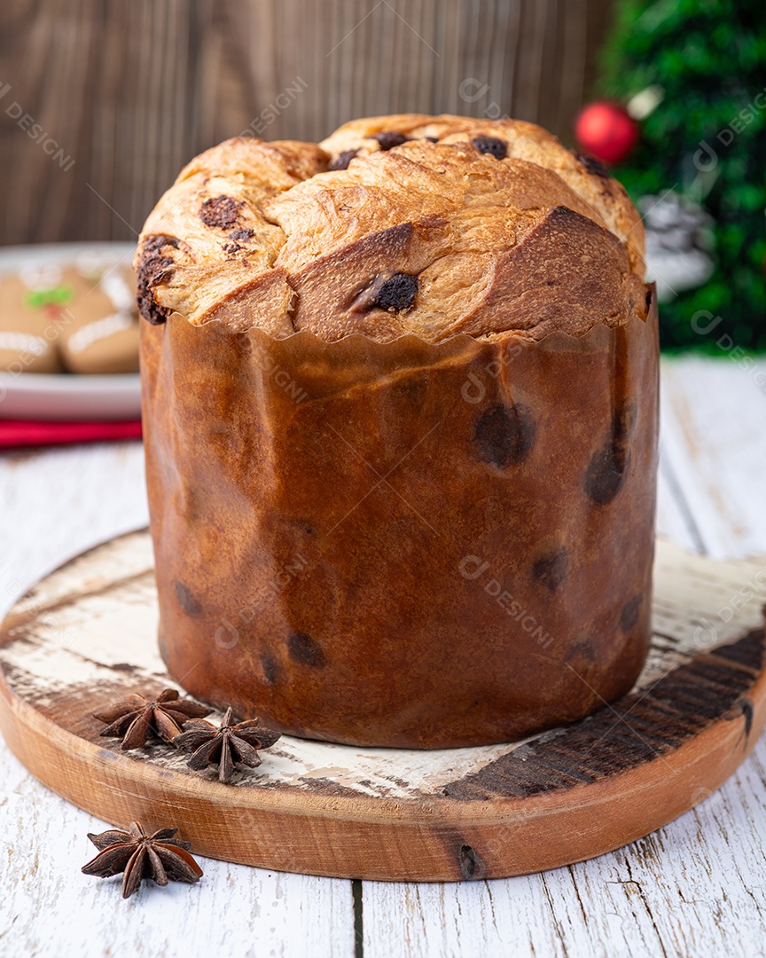 Panetone de bolo italiano tradicional com gotas de chocolate sobre a mesa de madeira branca.