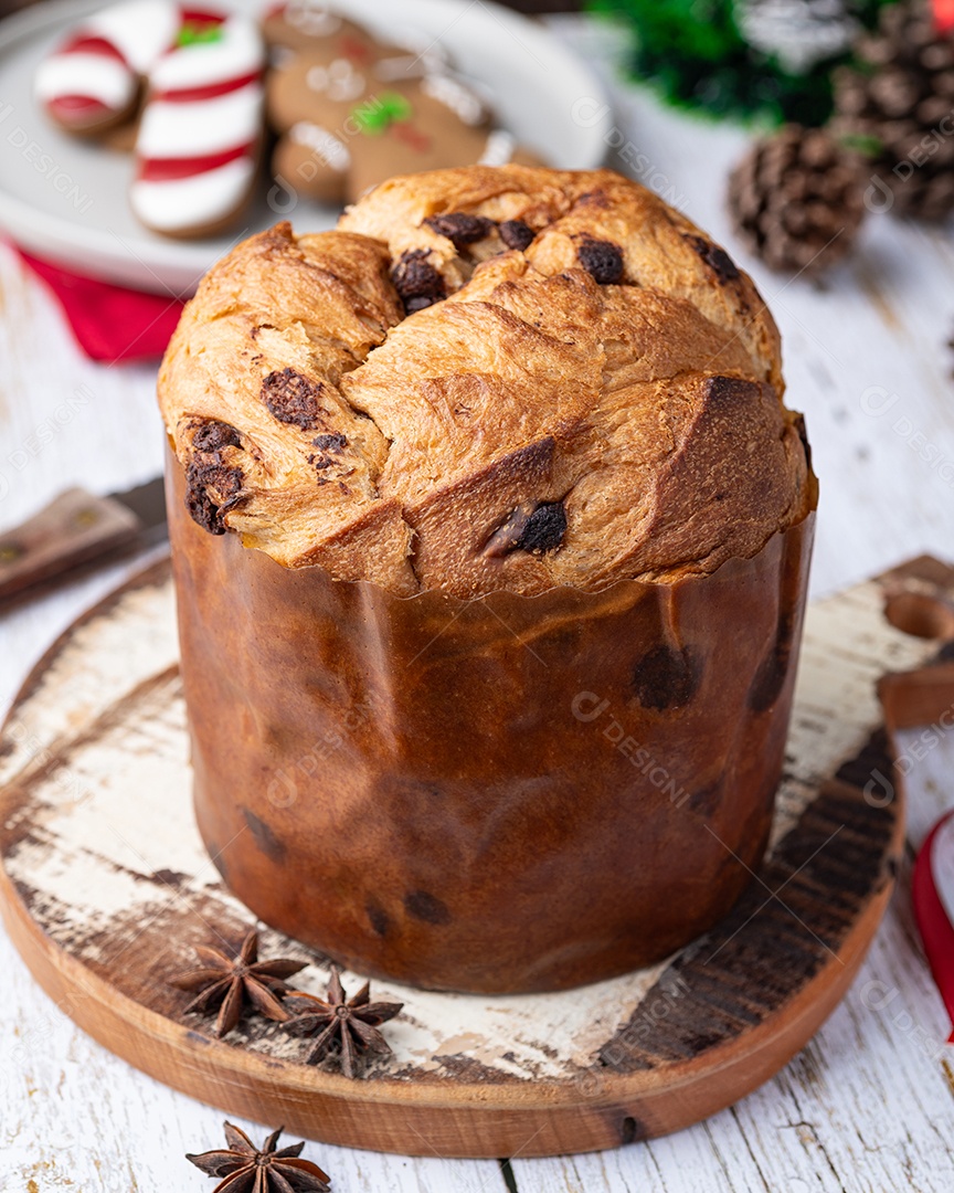 Panetone de bolo italiano tradicional com gotas de chocolate sobre a mesa de madeira branca.