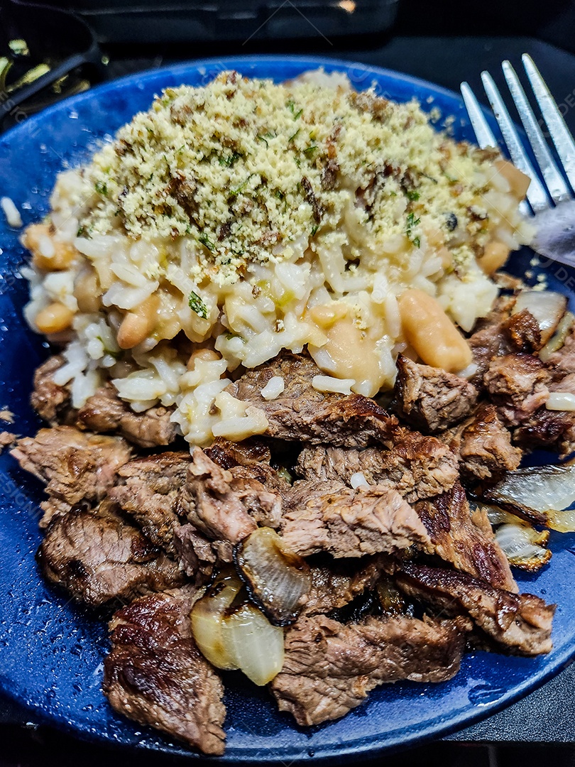 Prato de comida com carne arroz feijão e farofa sobre uma mesa