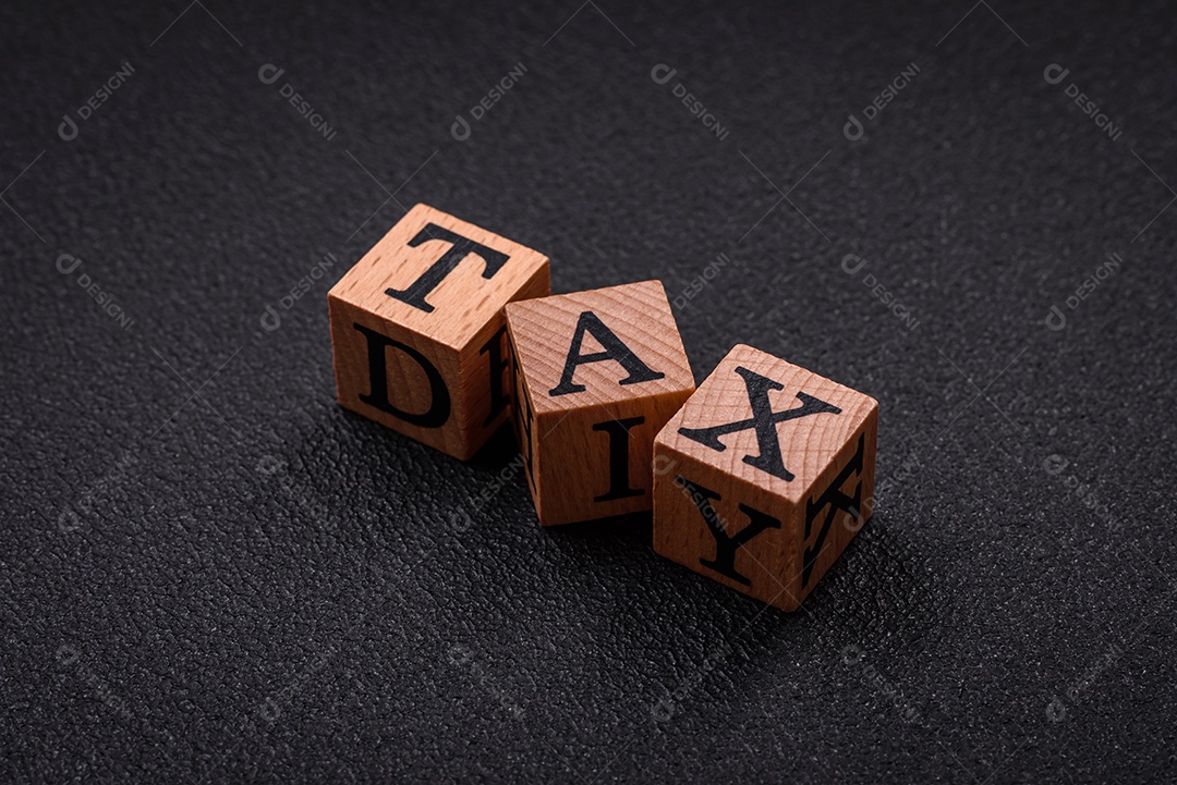 O imposto de inscrição em cubos de madeira sobre um fundo escuro de concreto. Pode ser usado como parte de sua composição