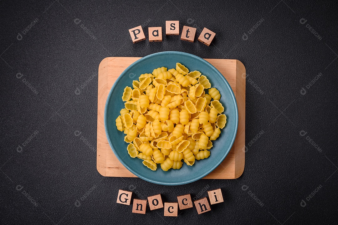 Massa de nhoque de trigo duro cru com sal e especiarias em uma placa de cerâmica sobre um fundo escuro de concreto