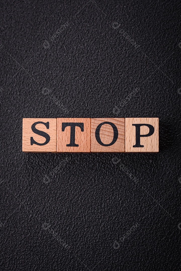 A inscrição para em cubos de madeira sobre um fundo escuro de concreto.