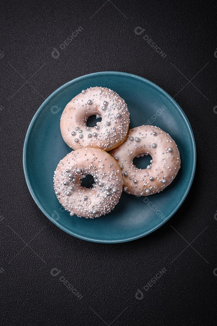 Delicioso donut fresco de cor branca ou bege com contas prateadas e creme sobre um fundo escuro de concreto