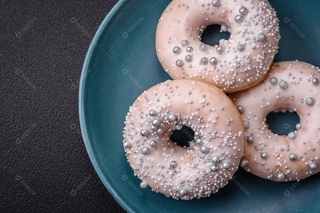 Delicioso donut fresco de cor branca ou bege com contas prateadas e creme sobre um fundo escuro de concreto