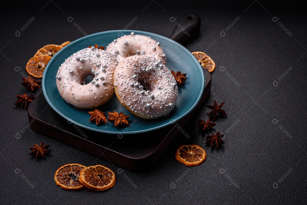 Delicioso donut fresco de cor branca ou bege com contas prateadas e creme sobre um fundo escuro de concreto