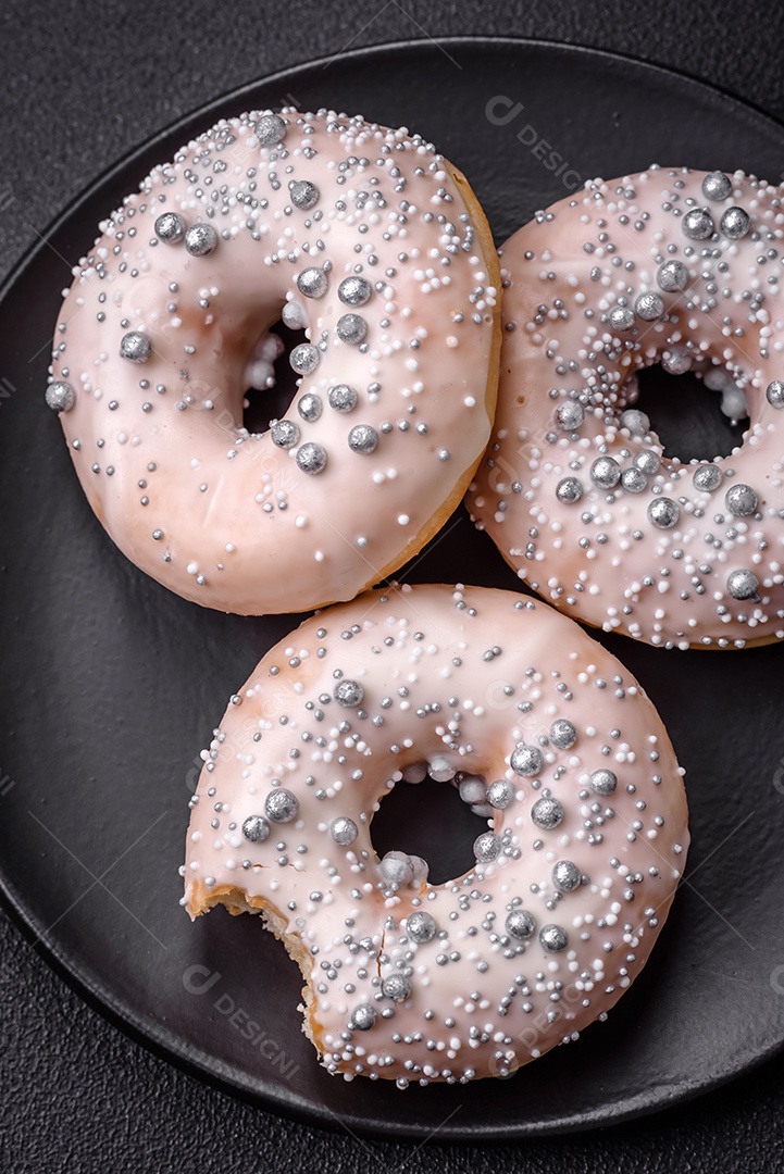 Delicioso donut fresco de cor branca ou bege com contas prateadas e creme sobre um fundo escuro de concreto